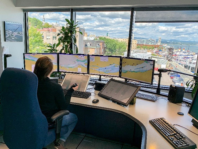 Jessica Morneau working as MCTS officer. Hard at work, looking at 4 computer screens.