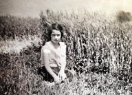black and white photo of Ardath Crooks-Zwicker, at a young age, posing in front of the wheat on Country Island.