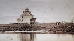 Old black and white photo of lighthouse and dwelling. Around 1930. 