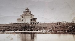 Vieille photo en noir et blanc d'un phare et d'une habitation. Vers 1930.