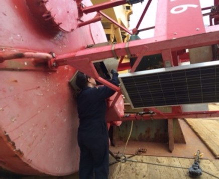 Melanie repariring a large, red buoy on a Coast Guard Ship.