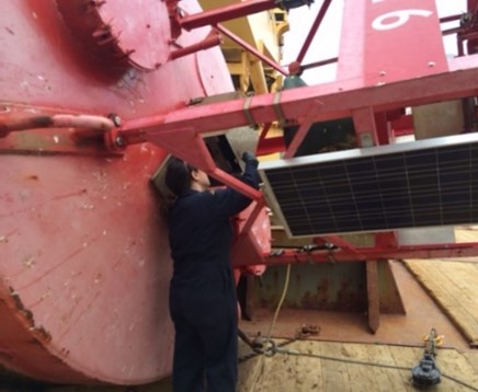 Mélanie réparant une grande bouée rouge sur un navire des garde-côtes.